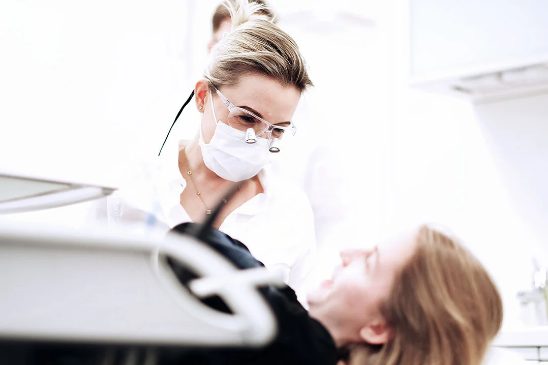 Frau Doktor Krieter lächelt freundlich eine Patientin an, die auf einem Behandlungsstuhl in der Praxis in Regensburg liegt