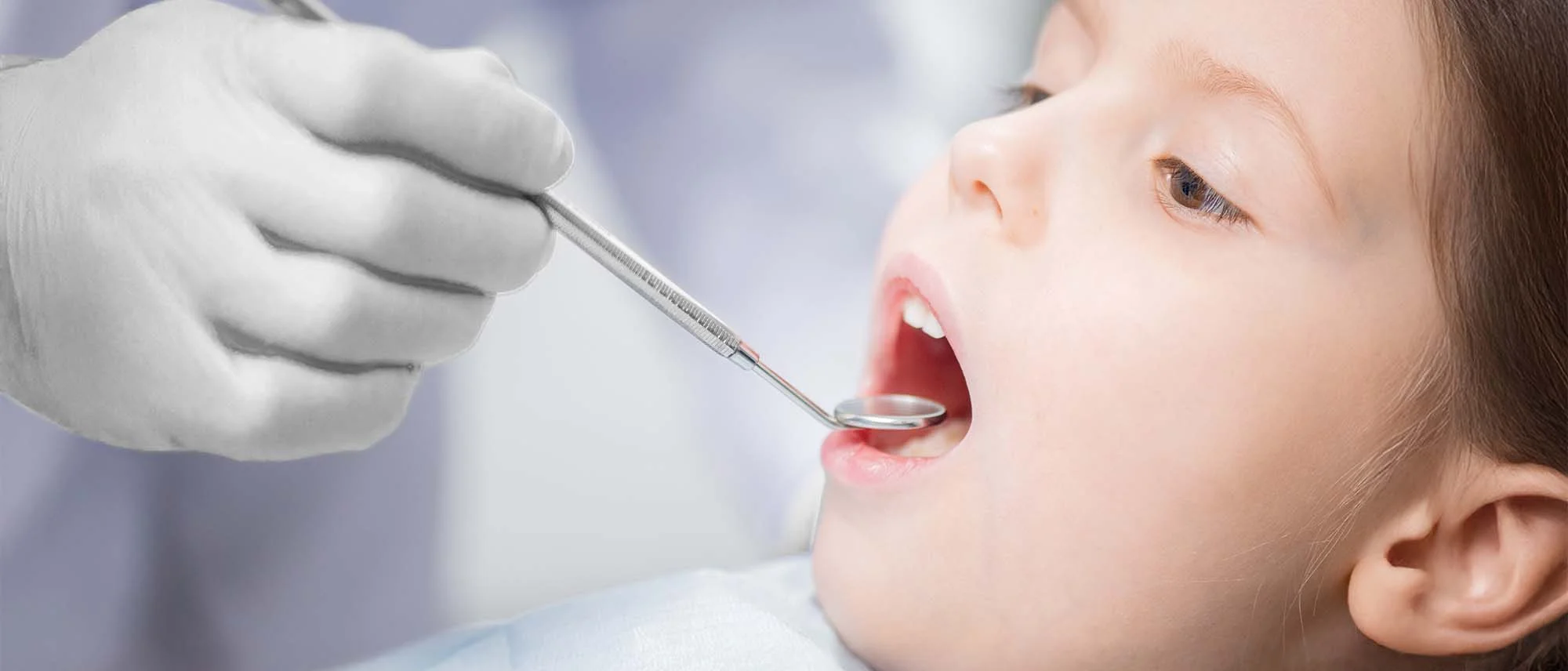 Child is examined by a dentist using a dental mirror