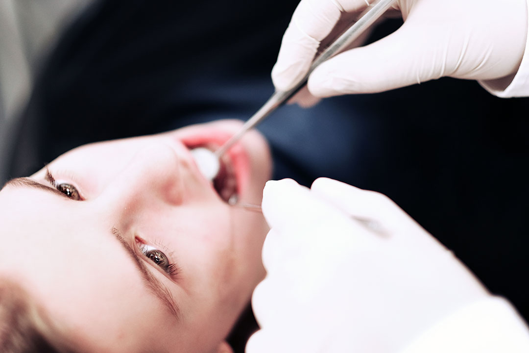 Patientin wird mit Mundspiegel untersucht während einer zahnärztlichen Untersuchung in Regensburg